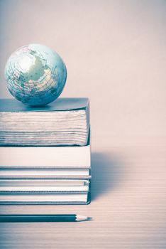 book and earth ball with black pencil on wood background vintage style