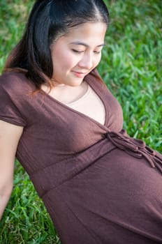 Pregnant woman sitting in the park . in anticipation of the child. Senses of tenderness, love and motherhood. toned photo