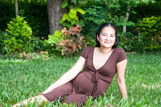 Pregnant woman sitting in the park . in anticipation of the child. Senses of tenderness, love and motherhood. toned photo