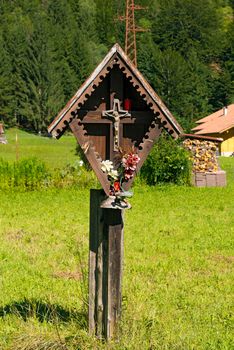 Typical wooden wayside shrine with jesus on cross in Italian alps. Trentino Alto Adige, Italy