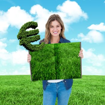 Woman holding lawn book against blue sky over green field