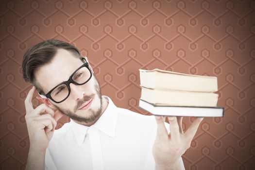 Geeky young man looking at pile of books against background