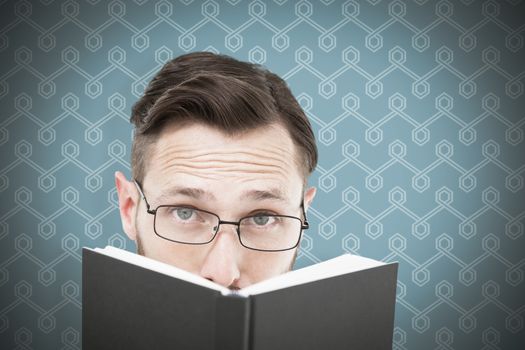 Young geek looking over black book against background