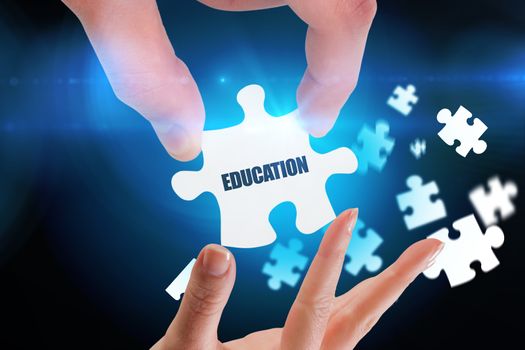 The word education and hands holding jigsaw against blue background with vignette