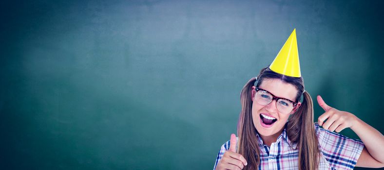 Geeky hipster smiling at camera thumbs up against green chalkboard