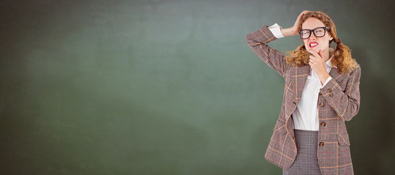 Geeky hipster thinking with hands on chin and temple against green chalkboard