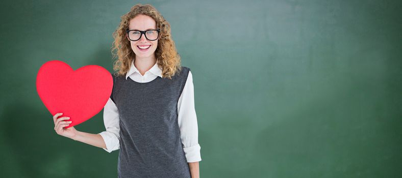 Geeky hipster holding heart card against green chalkboard