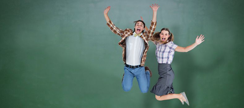 Geeky hipsters jumping and smiling against green chalkboard