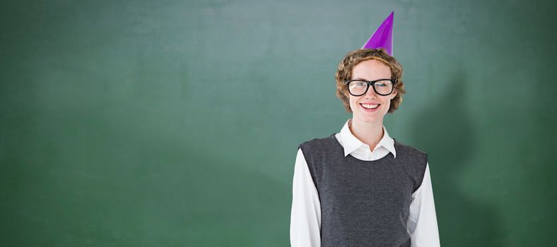 Geeky hipster wearing a party hat against green chalkboard