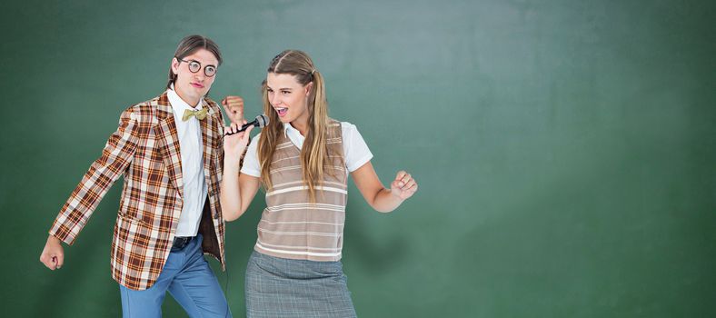 Happy geeky hipsters singing with microphone against green chalkboard