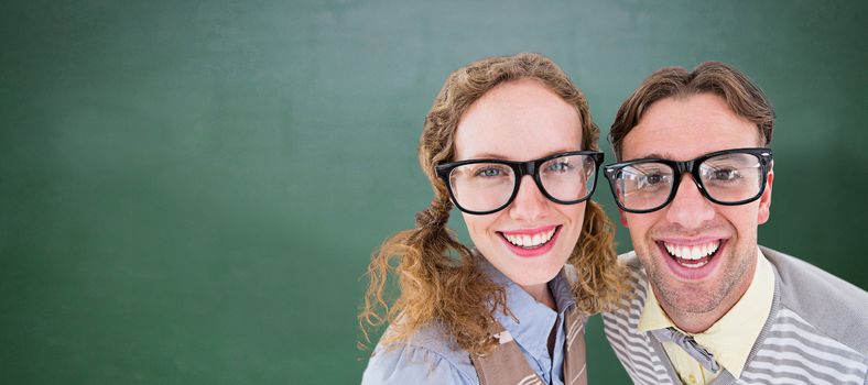 Happy geeky hipster smiling at camera  against green chalkboard