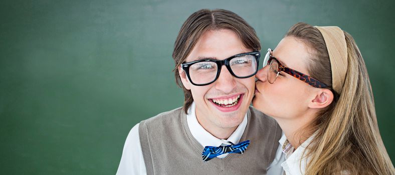 Geeky hipster kissing her boyfriend  against green chalkboard
