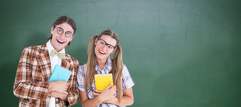 Geeky hipsters smiling at camera  against green chalkboard
