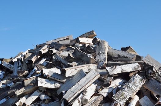 A Pile of Dry Chopped Cleaving Birch Firewood Against the Blue Sky