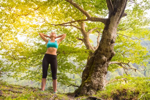 Active sporty girl raising arms, feeling  relaxed and free in beautiful natural environment. . Concept of natural, active, healthy, lifestile.