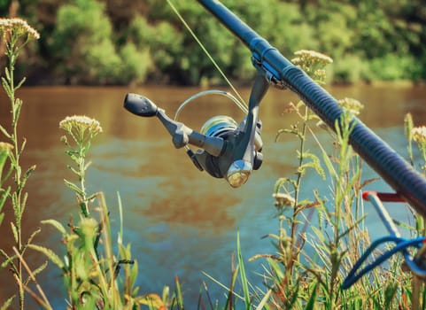 On the banks of the beautiful river above the water feeder installed - English fishing tackle for catching fish comfortable with the rod and the reel.