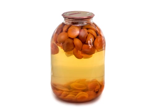 Home canning: a large glass cylinder with apricot compote, sealed metal lid. Presented on a white background..