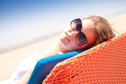 Young woman relaxes on a lounger on the beach