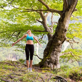 Active sporty girl raising arms inhaling fresh air, feeling  relaxed and free in beautiful natural environment. . Concept of natural, active, healthy, lifestile.