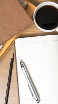 open notebook with book and coffee cup on wood background