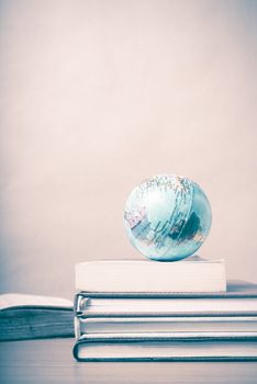 book and earth ball on wood background vintage style