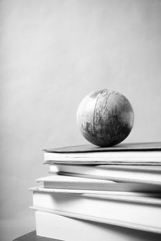 stack of book and earth ball on wood background black and white tone style