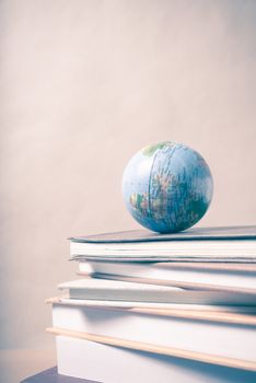 stack of book and earth ball on wood background vintage style