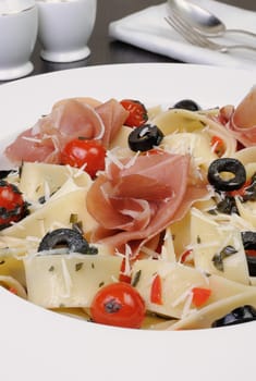 plate of spaghetti with jamon, tomatoes, olives and parmesan