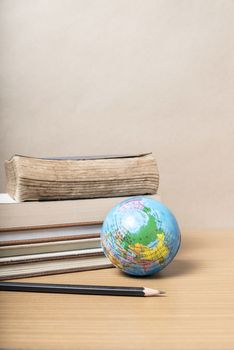 book and earth ball with black pencil on wood background