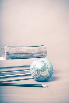 book and earth ball with black pencil on wood background vintage style