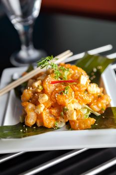 Thai crispy shrimp dish with apple and sesame seeds presented beautifully on a white square plate with chopsticks.