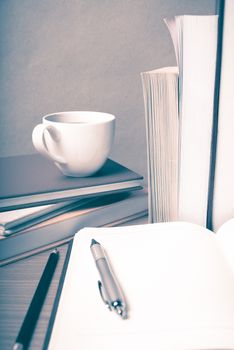 open notebook with book and coffee cup on wood background vintage style