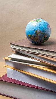 stack of book and earth ball on wood background