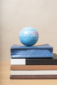 book and earth ball on wood background