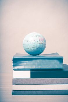 book and earth ball on wood background vintage style