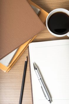 open notebook with book and coffee cup on wood background