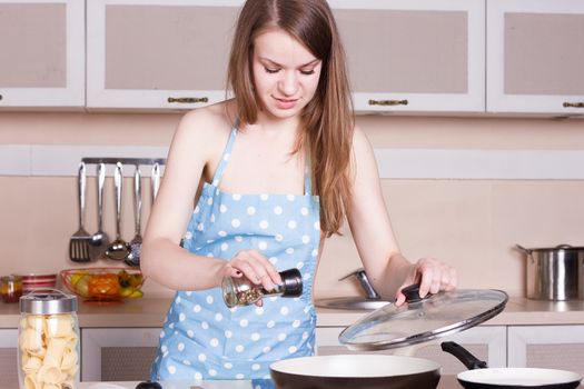 Girl in a apron over his naked body in the kitchen preparing