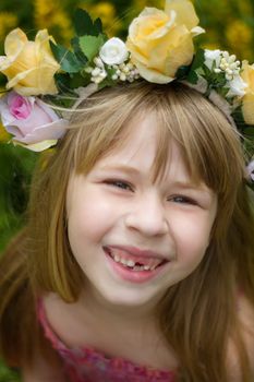 Girl 6 years old in a wreath. Smiles. Baby teeth fall out.