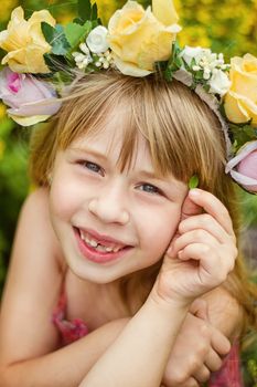 Girl 6 years old in a wreath closeup. Smiles. Baby teeth fall out.