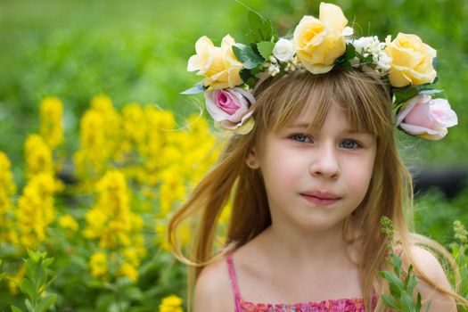 Girl 6 years old in a wreath in the meadow.  Horizontal framing