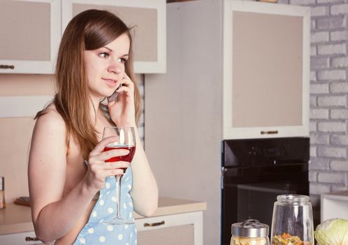 girl in the kitchen wearing an apron over his body with a glass of wine