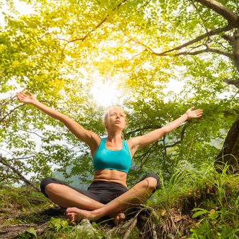 Relaxed woman enjoying freedom and life in beautiful natural environment. Blissful girl raising arms, feeling free, relaxed and happy. Concept of freedom, happiness, enjoyment and natural balance.