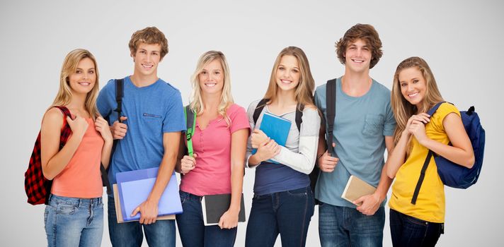 Smiling students wearing backpacks and holding books in their hands against grey vignette