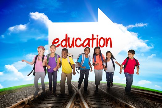 The word education and elementary pupils running against railway leading to blue sky