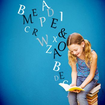 Cute little girl reading book in library against blue background