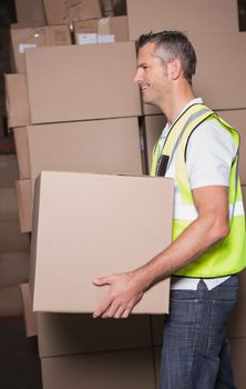 Side view of worker carrying boxes in the warehouse