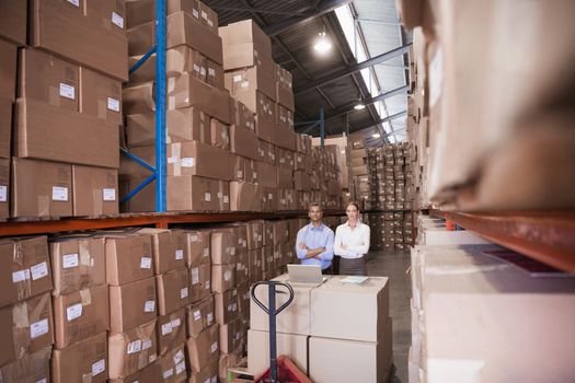Manager and colleague with laptop at work in warehouse