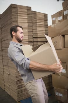 Side view of worker carrying box in the warehouse