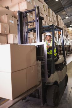 Driver operating forklift machine in warehouse