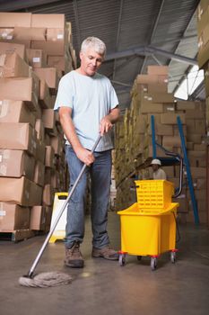 Full length of man moping warehouse floor